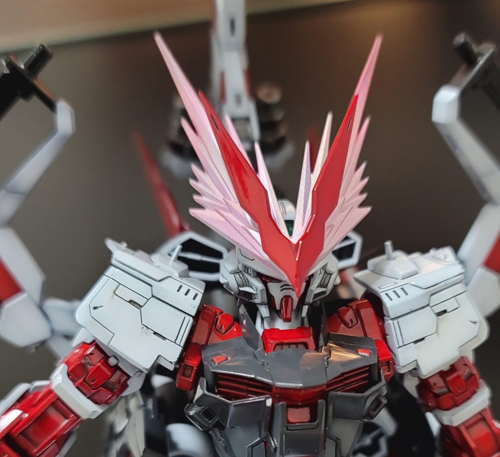 肩、胸部肩はスジボリ+プラ板で面構成を変更。複雑な多重装甲ぽくなるようにしてみました。垂直翼みたいなのをいくつか配置、地味に胸部にも追加しています。胸部中央にチラ見えするフレームは彫刻刀で開口しダクト風に肩の3連スリットはガッツリ彫り込んだところに平棒を組んだ物を埋め込む方式でやってみました。ツノのビームはガンダムマーカーのトランザムホロレッドを吹いてみました。偏光がいい感じです。