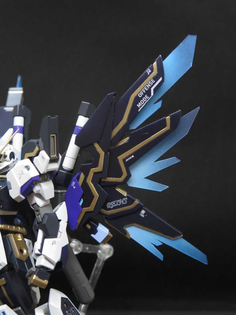 ミノフスキードライブ“スレイプニル”開発コートネームはブレッシング．ウィングス(祝福の天翼)、撤去したスラスターバインダーの代わりに取り付いたミノフスキードライブ型推進翼と追加ジェネレーター。三枚羽を形にしたユニットの内部でミノフスキー粒子の力場を発生と衝突させ、その反動を任意の方向に放出する事で推進力としている。使用時はスラスターから高密度のミノフスキー粒子が噴出し、副次効果として生じる荷電粒子の余剰エネルギーはIフィールドで翼状のビーム刃に一旦抑え込み、あとで光の翼という形で放出する。本機の場合では推進口を3方向に分けることで内圧管理改善や小回り機動の特化を図り、完成度を高めた仕様になっている。下部には排熱装置が付けており、使用時は下部カバーをスライドすることでエアダクトを露出し、強制放熱する。