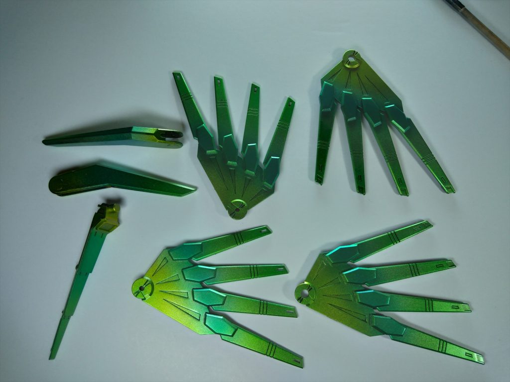 塗装ラストに持ってきた背中の金羽は、νガンダムのサイコフレームを意識してクリアグリーンメインに、クリアブルー、クリアイエローでグラデーションにしました。結果サイコフレーム云々より、昔買ってたセキセイインコがこんな色だったな、と思い起こさせてくれる、なんとも微妙な物体に仕上がりました。これはもう装着するまでイメージ湧かない感じでした。