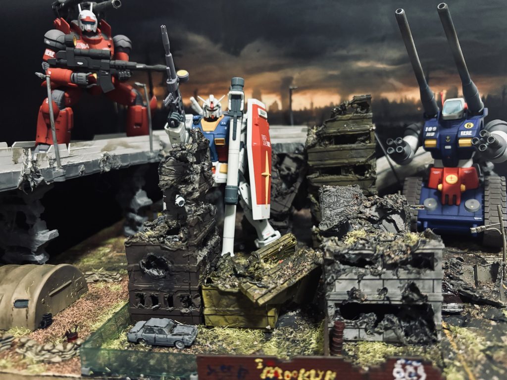 背景はフリー素材を使って、ジオラマは、主にバンダイのカスタマイズシーンベースを二つ使って、ダメージと汚しました。