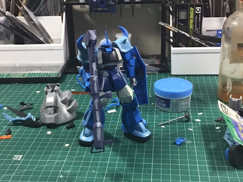 リバイブグフの改修箇所はグフカスのショルダーと足を交換。ショルダーのスパイクをコトブキヤのキットに交換して胸の厚さプラ板で2ミリボリュームアップ、コクピット周りもエポキシパテでボリュームアップ。モノアイスリットの幅を狭くする為頭の真ん中を切断してプラ板を挟んで狭め目つきを悪くして、モノアイはハイキューパーツのカメラに交換。スタビライザーはグフカスの物を薄くヤスリ、腿はプラバンで2ミリ延長。腿が細いのでエポキシパテで太らせて、手とバックパックのバーニアは市販のキットに交換。左腕とシールドはネオジム磁石を埋め込んで接続。プラ板でスカートの幅増し。胴体、腕、脚にスジボリ等のディテール追加しました。塗装はブルーはクレオスのコバルトブルーをベースにパープル、ホワイト、蛍光ピンクで調色した淡いブルーをエアブラシで塗装しました。