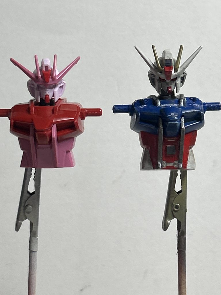 『じっと目を凝らしても　見失ってしまう星』では以下は改造点をば。頭部は、アンテナの白い部分及びメインカメラをEGの物に変更、アンテナ基部の赤いパーツはHGCEの物(多分)を取り付け、アンテナの黄色の部分は旧HGの物を加工して付けました。フェイス部分はビルドバーニング(おそらく)の物から流用です。メインカメラの色分けはめんd……いえ、思い付きでメタルシールをクリアレジン封入と言う形で作成しました。胴体は、青部分の中央をパテで盛り上げ、それと後ハメとお腹と腰の境界部分で部分で2ミリほど嵩上げ、あとは適当なディティールアップパーツで装飾。首が埋まっている印象だった為、根元で1ミリ延長しました。そのおかげで首の可動範囲が相当広がりました。あと、背面のメインスラスタが旧1/100と同じくディテール不足である為開口し何かありますよ感を演出。以下備忘録。次作る時は胴体部のフレームを別パーツ化を視野に入れていても良いかも。理由としては凸凹でマスキングが手間。以上備忘録終わり。