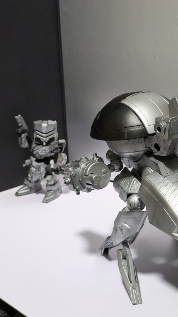 まあ、見えるかどうか、多分見えませんがロボコップのED-209をモデルにウォドムポッドをちょっと改造。といっても脚部を逆にして逆関節に、両腕にガトリング(短)を両腕に取り付け、シルバーメインで塗装しただけのお手軽ミキシングですw背景のロボコップもどきは過去作より。