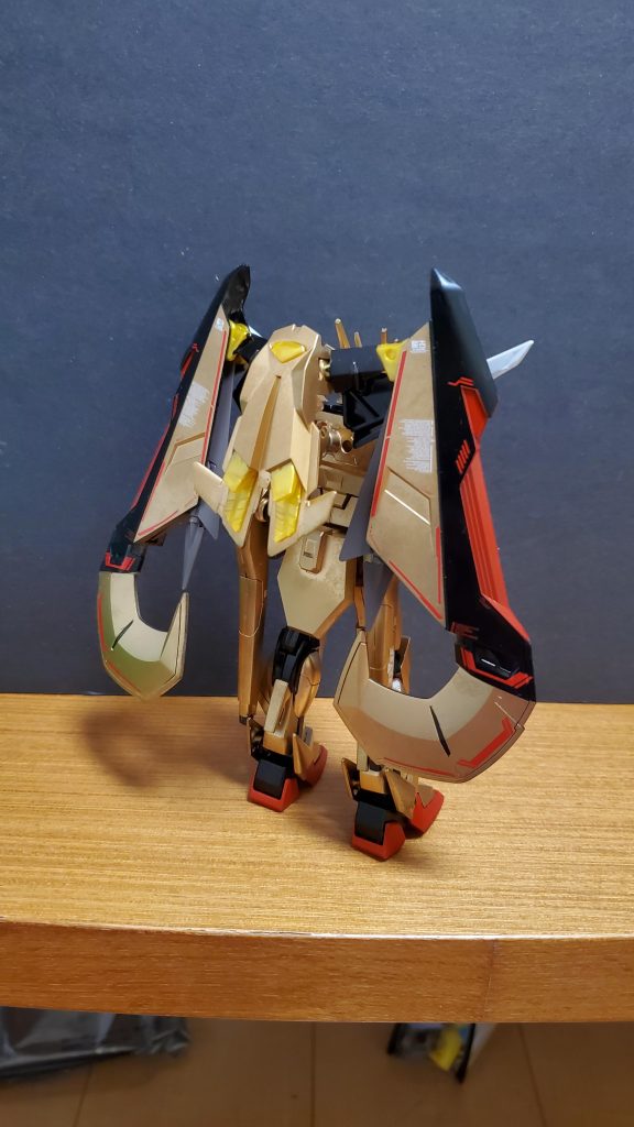 機体解説②:背部にはマガノイクタチを装備している。マガノイクタチは敵のエネルギーを強制吸収し無力化させることを目的とした兵器である。殺傷能力を向上させるよりも、敵の戦闘能力を奪い無力化させることに重きをおいたカガリの提案により採用されている。アカツキ改に搭載されているものは、ゴールドフレーム天のデータを元に改修し、完成させた新型である。また、黄金色の目立つ機体に国家の元首が乗り込むのはいくらなんでもリスキーだと言う声が多く上がっていた一方で、レクイエムから祖国を守りきった本機を肯定する専門家もいた。そこで、本機ではゴールドフレーム天よりミラージュコロイドステルスシステムを引き継いだ。CE76ではミラージュコロイドステルスシステムを黒色以外の装甲にも纏えるようになっていた。(現にフリーダム劇中ではズゴックが使用)本機はパイロットの生存性と隠密性を向上させるため採用された。また、本機から動力源が核エンジンになったためミラージュコロイドステルスシステム常時展開できる。