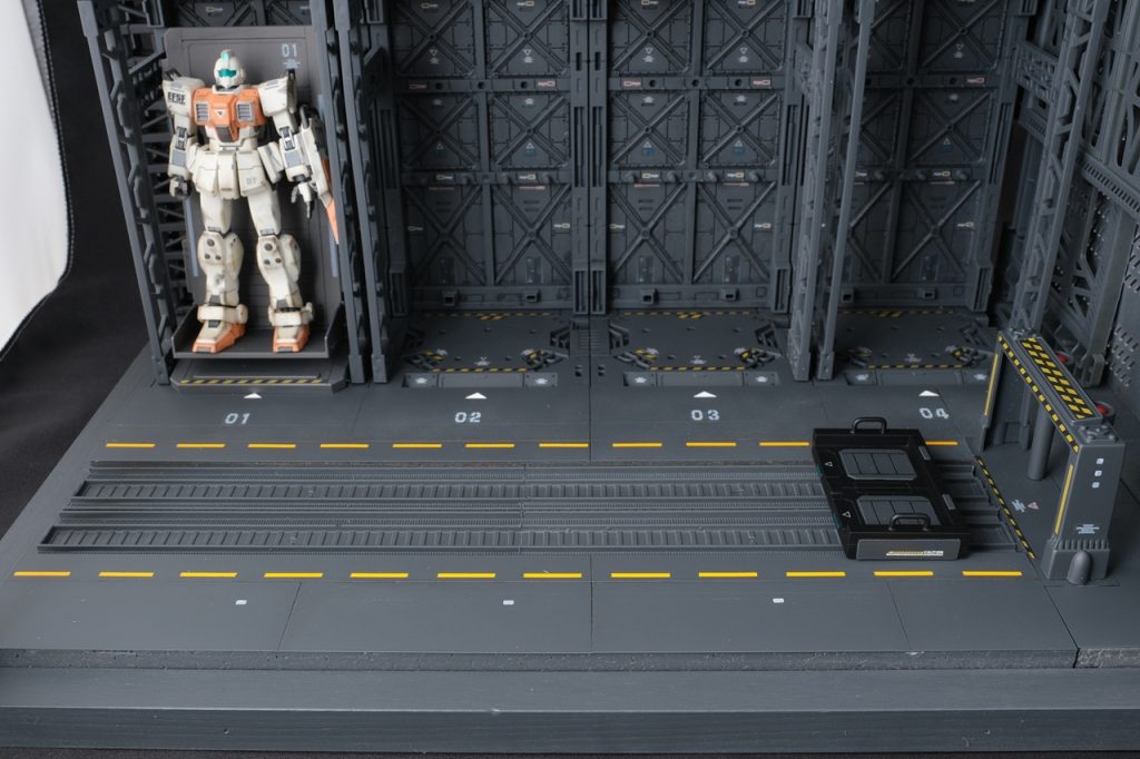 床面。レールに沿った黄色いラインは、下に黄色を塗ってマスキングをし、上からブラックグレーを塗っています。01などの数字の上にある矢印も同じ方法で白く残しています。レールの高さに合わせるため、スチロール板の上にプラ板を敷いています。ディスプレイベースの床面とも同じ高さになっています。