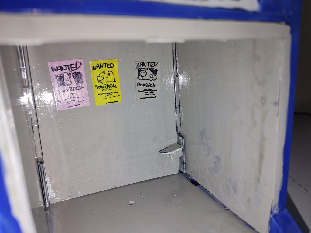 内部。プラ板製のボーゾック指名手配ポスターに、陳腐な(・・;)棚?