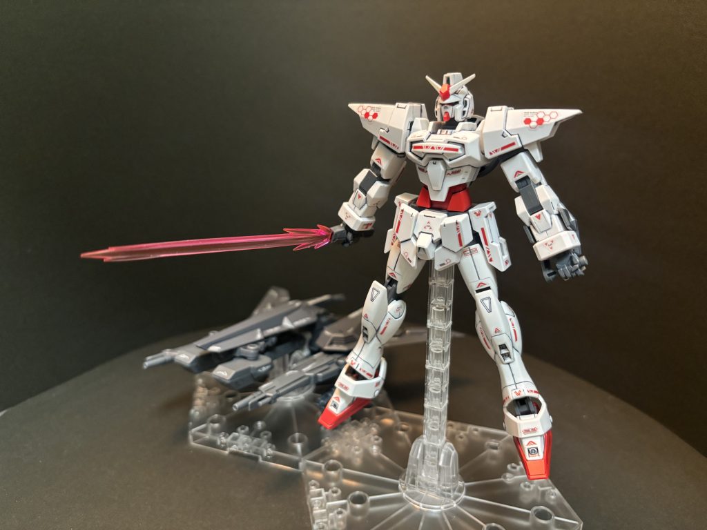 【脳内設定】Gバウンサーをベースにマッドーナ工房で製作された技術試験用MS。テストパイロットはGバウンサーに引き続きウルフ・エニアクル。AGEデバイスの中に封印されていた「Oガンダム」や「シルエットシステム」という遥か昔の戦いで使われたとされる兵器群のデータを参考にしており、ウェア以外の追加パーツによる機体特性の変化と有効性を検証するために使用された。動力は通常の核融合炉+GNドライヴ[N]の2種連結式ジェネレーターを採用。高い機動性を維持しつつ出力の大きい武装を状況に応じて展開するというコンセプトとして完成。起動中のバランスを考慮し、機体の主要な機能はMS本体に集約させつつ追加パーツを支援機に装備させて随伴する事で、本体と支援機の相互連携・換装による立体的かつ高度な戦術を生み出す事が可能。…ではあったのだが、ウルフ本人が近接・格闘戦を好みとしており射撃兵装をあまり好まなかった事、支援機に搭載されたAIのサポートがあるとはいえ2機の相互連携における操作が煩雑過ぎる事、ジェネレーター製造コストが高過ぎる事、搭載された武装に対してジェネレーター出力を持て余すほど高い事など、結局のところ悪い意味でピーキーな性能になってしまった。ウルフは数回の兵装テスト後に即座に元のGバウンサーへ乗り換えており、この機体はそのまま地球連邦軍によって兵装テストに使用される事となる。変形合体等のデータは後世のクランシェやアデル等の新機体開発に活用された他、ジェネレーター出力の高さを活かした新型ウェアのテストにも用いられた。…後にこの機体が保管されている基地をヴェイガンが襲撃する事件が発生し、「ウルフ・エニアクルの息子」を自称するXラウンダーの少年がこの機体を駆ってヴェイガン機を迎撃する事になるのだが、それはまた別のお話。