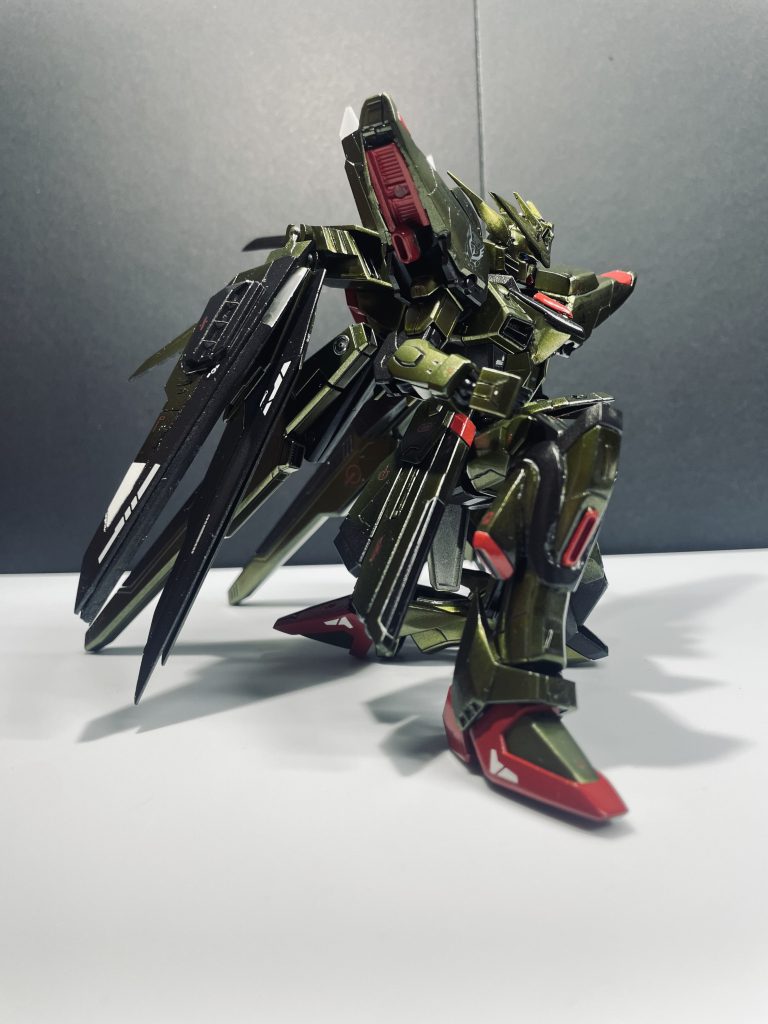 造形に関してはフリーダムをアカツキ風に改造する上でアカツキ自体のパーツを持っていなかった為殆どをプラ板やパテでセミスクラッチという形で制作しました。特に目立つのはバックパックの変形だと思うのですがこれはアカツキの大鷲のような形からフリーダムのハイマットフルバーストのように羽が展開するギミックを搭載したかった為試行錯誤した結果ビルドストライクフルパッケージのビルドブースターのギミックを運用。実際ビルドブースターも持ってなかったので上2枚の羽はプラ板から整形してます。羽の展開軸はランナーをプラ棒変わりにし広げられるよう調整しています。