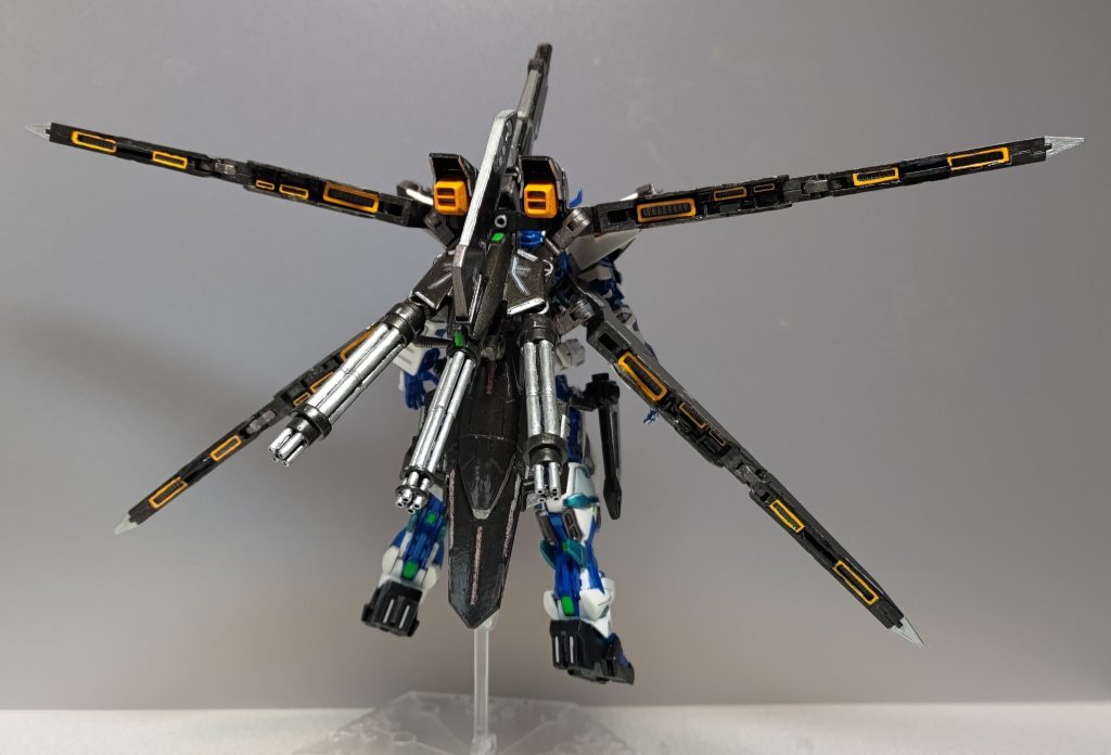 バックショットです。ネオタクティカルアームズはフォールディングアーム(ウェポンユニット42)の基部を中心に各アームパーツでタクティカルアームズのソード部を接続してます。また固定兵装としてビームキャノン(パワードアームズパワーダー)を追加しました。機体背面にマウントしているときは頭上に構えます。ご注目いただきたいのはソード部の峰にビッシリ埋め込んだバーニア！　ダクトノズル(プラユニット P-104)をワンセットまるまる使いきって大型フレキシブルスラスター兼ソードに改造してます。塗装にあたって、青白メインの機体に黄色や金色を差そうかと思ったんですが、このバーニアたちを強調したくてやめたんですよ。元タクティカルアームズのガトリングは、ソード部の代わりにガトリング(パワードアームズパワーダー)を2門装着し、トリプルガトリングアームとして別装備にしました。背中にマウントするときに後部のスラスターを折り曲げて、砲門とともに後方へ向けるギミックは健在。以下、アクションポーズです。