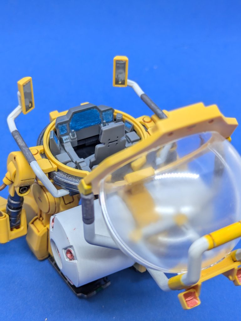 背中側から見た状態。コクピットのモニターっぽい部分はメタリックブルーで塗装しました。サイドミラーっぽいパーツは、付属のシールを貼っています。背中のスラスター兼プロペラントタンクっぽいパーツは設定上はグレーですが、なんか違和感があったので、サーフェイサー吹いて白くしました。バーニア内部はメタリックレッドで塗装しました。