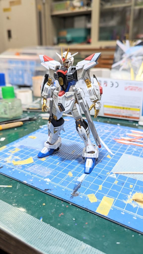 塗装、スミ入れ、デカール、つや消しが終わった状態。ディテールの追加白の塗り分けMGEXに似せた形状への変更(前腕・股間・膝)各所のシャープ化を主に行っています。よく見ると後ろに転がっているプラウドディフェンダーですが、こちらも肉抜き埋めや、例の四角いカバーパーツとの隙間を埋めたりという処理を行っています。 