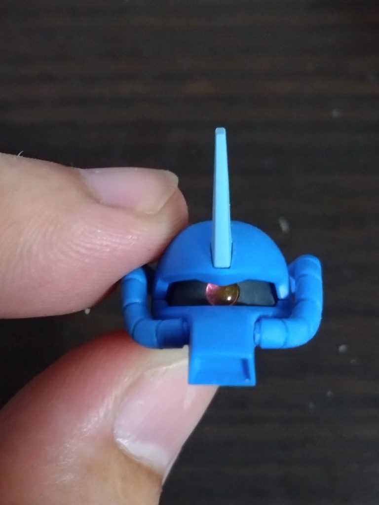 頭部のアンテナは形状的にグフカスタムのモノが近かったので、グフカスタムのモノを流用。接続部は無加工で綺麗にシンデレラフィットします。気持ち緩いかなぐらいですね。モノアイはHアイズに置換。画像ではピンクをハメてますが、本番ではレッドにしました。リバイブグフのモノアイシールドは構造が妙で、なぜかモノアイ周辺が盛り上がった造形で、そこにモノアイのディテールがあるんですよね。ちょっと不自然過ぎると感じたので、その凸を削り落とす形にしています。ただ…