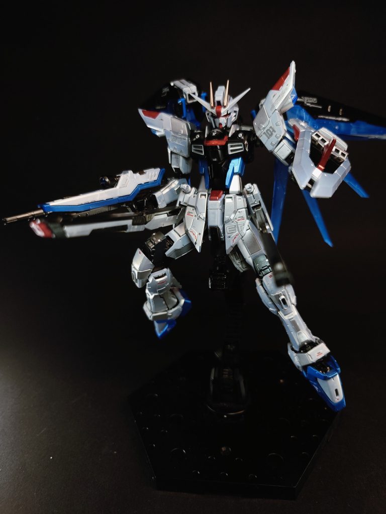 MMI-M15 クスィフィアスレール砲×2[注 31][注 3][注 32]デュエルのアサルトシュラウド用装備である「115mmレールガン シヴァ」を発展させた、折り畳み式電磁砲[22]。また、可動式のスラスターユニットとしても機能する[69][注 33]。展開時の砲身全長が原型装備よりも長くなったことで、より高速での発射が可能となっており[40][注 34]、ランチャーストライクの火力に匹敵するとされる[1]。広い射角と膨大な携行弾数を有し、マルチロックオンシステムとの連携によう広範囲攻撃が可能[22][注 35]。多くの戦闘ではサイドスカートの固定装備として使用される兵装であるが、デザインにおいてはバレルから側面に展開するグリップも用意されている[注 36]。レールガン自体はG兵器がもたらしたビーム兵器によって主力武装の座を奪われるものの、MMI社の技術陣はビーム兵器に対して高い防御能力を有する「ラミネート装甲」が一般化した戦闘における対艦船攻撃用武装としての重要性や、連射性を活かした複数の標的への同時攻撃能力の高さなどを理由に、本機への当武装の搭載を押し切った[68]。