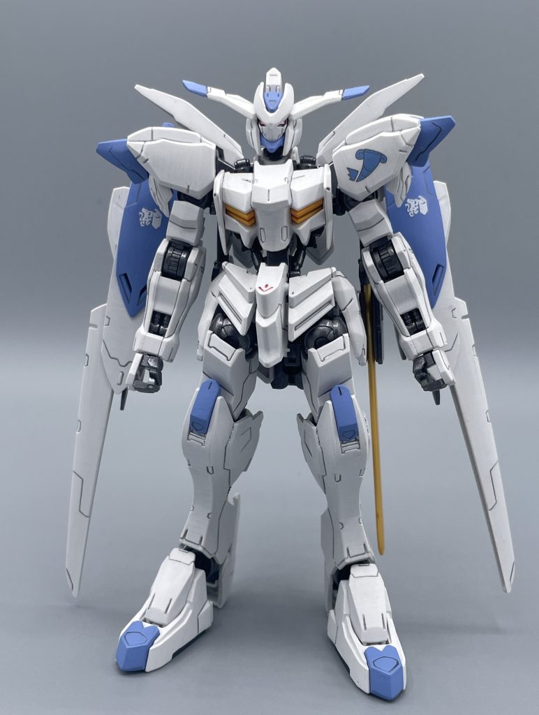 ASW-G-01　GUNDAM BAEL　三百年前の厄災戦。それは、人類の総人口の４分の１を失う大戦であった。人間を虐殺するキラーマシンであるMA（モビルアーマー）を前に、人類は悪魔の名を冠するMSを生み出すことによって対抗した。　人類の切り札、それは〈阿頼耶識システム〉と呼ばれる機体にパイロットを直接接続させることにより、機体の運動性能を飛躍的にブチ上げるというシステムであった。　〈阿頼耶識システム〉は、莫大な戦闘力を手にすると同時に、人体にも強大な負荷を強いるという、残酷なものであった。つまり、MSに乗ることは〈悪魔との契約〉そのものだったのである。　ガンダムバエルは、パイロットであるアグニカ・カイエルと共に、人類を勝利に導いた機体であり、厄災戦終結後に結成されたギャラルホルンの象徴とされた。ギャラルホルン本部で３００年の眠りについたアグニカとバエルは神格化されていき「バエルを操るものはギャラルホルンを統べる」という伝説を生み出していく。　永き眠りの間、バエルと仲良くなろうとする者は度々現れるもことごとく失敗。しかし、３００年の時を経て、大量のアグニカポイントを貯め込んだマクギリス・ファリドによって、バエルは永き眠りから目覚めることとなる。