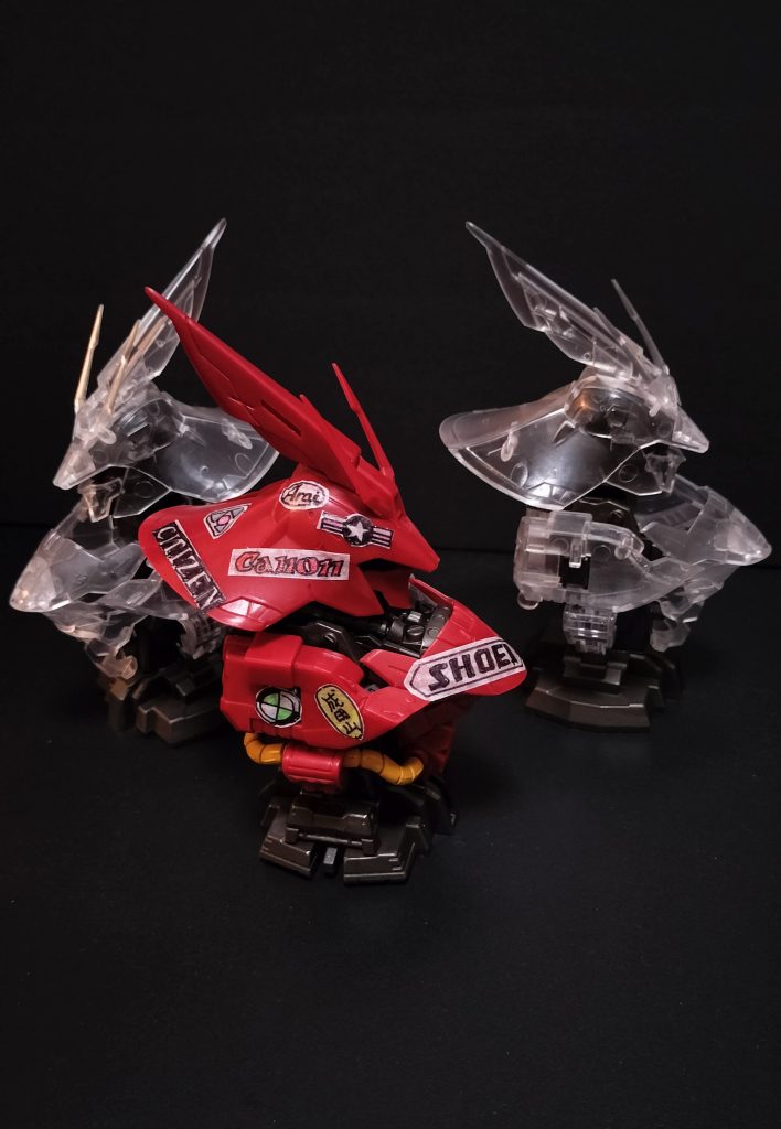 フルサイコフレームのチートニューガンダムを駆逐すべくダイクン総帥によって発令されたサザビー量産指令で、ネオジオンのパイロット全員にサザビーが支給されることになった。どれも赤いサザビーに仕上げられるので、一般パイロットたちは自分の乗機のパーソナライズに腐心した。ネオ・トーキョー出身のハインリッヒ・カネダ曹長も、そんなパーソナライズに悩んだ一人だ。悩んだ末にたどり着いたのが、自分の父方先祖にルーツのある旧世紀のニッポン発のサブカルチャーをモチーフにするアプローチだった。旧世紀の上映当時一世を風靡したというアニメの主人公のマシンが赤かったこと、主人公の名前と自分の姓が同じであったことにも親しみが湧き、主人公のマシンのステッカーチューンをオマージュしたパーソナルカラーリングとなった。当然そんなロゴのステッカーなどは手に入るわけもなく、全て手書きで”それらしきもの”を自作したという。なお、当人はそれらステッカーがなんのブランドなのか、まったくわかっていないらしい、というのがもっぱらのウワサだ。