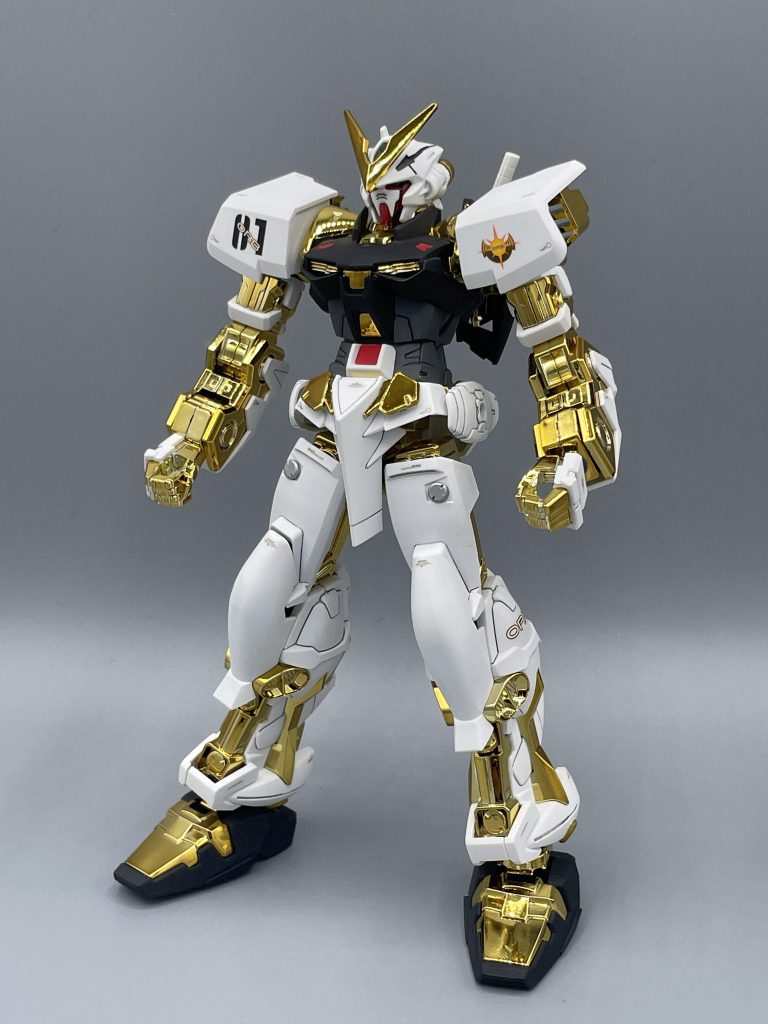 素立ち。なんもしてなくても、存在感がすごいです。ヴィトンのプラモかね、君は。 各所のマーキングが謳っているように、アストレイなのでオーブで作られたMSです。そして、これまたアスラン達ザフト軍がヘリオポリスを侵攻した際に、オーブ五大氏族に数えられるサハク家のロンド・ギナ・サハクによって持ち出されました。この五大氏族ってのは、「オーブ連合首長国の政治は、選挙によって選ばれた議員と、古くから国の中枢を担ってきた五大氏族によって運営されている」とのことらしくて、ガチモンのゴリゴリ貴族様です。 グリーンフレームはヘリオポリス崩壊で粉々になりますが、このゴールドフレームはギナ様のおかげで難を逃れました。その際、実は”あるモノ” も一緒に持ち出していて・・・