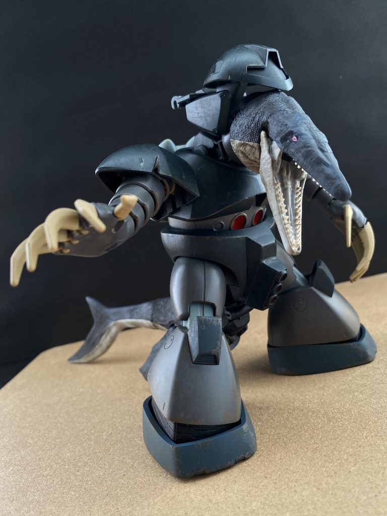 型式番号不明(MSM-03？) モサゴッグ(仮名)　シャークゴッグの評価試験中に現れた謎のMS。その外見は、ゴッグのようだが、まるで生き物のような頭部、尻尾(ヒレ？)を持つ。凄まじいまでの水中機動性能を持ち、推測ではあるがある程度のステルス性能も有しているようだ。おそらく火器の類は搭載されていないか、すでに弾切れ(補充されていない)なのか、シャークゴッグとの交戦の際、両手のクローを始め、尻尾や、顎による打撃攻撃が主な攻撃方法だった。　後の調査により、この機体はASLM社がシャークゴッグに先駆けて試作したMSであることがわかっている。稼働試験中に行方不明になったという記録が残っていただけであり、その他の機体に関するデータは何一つ残っていなかった。ただ謎なのは、パイロットはいたのだろうか？この機体は、MSなのか？…それとも「生物」だったのだろうか？　謎は深まるばかりである。