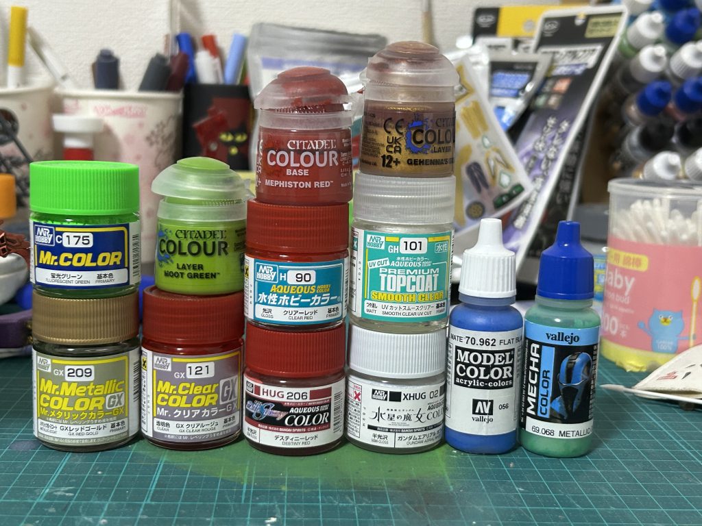 使ったカラー達(サフ除く)。ブラックのラッカーサフ吹いた後、レッドゴールドで塗装。そこから細かい色分けを各水性塗料(ファレホブルー、シタデルレッド、ガンダムカラーホワイト)などでやりました。SDはマスキングだと地獄になりがちなので私は拭き取り方式でやることが多いです。目については今回塗装再現で、ホワイトサフ→蛍光グリーン→デスティニーレッドで作成。この辺りも塗る順番や目専用マスキングを使い楽に作れるようにしました。シタデルのゴールド系は拭き取った後にくすんだりすることがあるので仕上げ兼調整などで使ってます。ファレホのメタルグリーンも割と同じような使い方です。クリアルージュは羽など主に星守愛に使ってます。その上から水性クリアレッドをオーバーコートしたり武者デスティニーにも使ってます。この辺りはやり易さと使う場所によって使い分けてます。