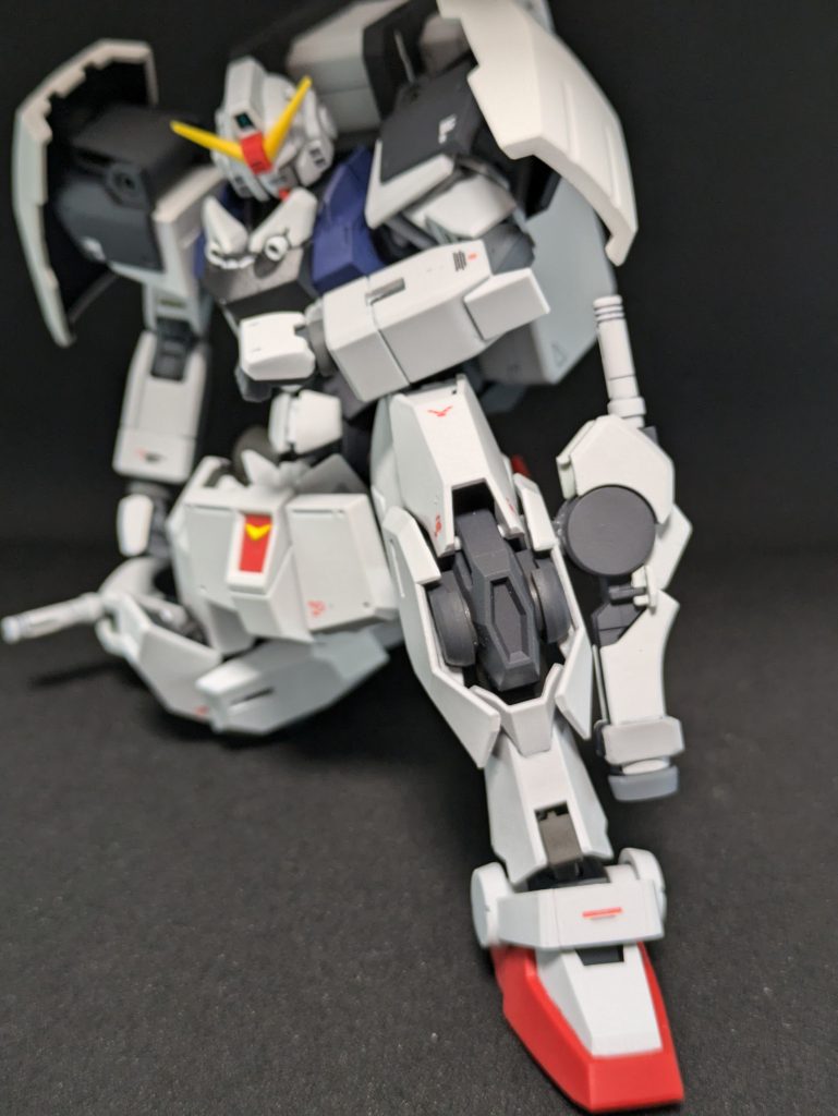 ガンヴォルヴァの脚の可動域とハインドリーの装甲が少ない分、片膝をついた姿勢もやすやす。このへんは水星の魔女系のいいところですね。まあ陸ガンもできるんですがね。本機体唯一の固定武器、ビームサーベルラックはザウォートの腕です。ビームサーベルは陸ガンのですが、1.5mmピンとか昔からずっと共通でいてくれたので採用です。丁度、ガンヴォルヴァ側に四角いスリットがあるのでそこにハマるようザウォートの肘のパーツを削って差し込みました。これ、どちらかといえば兼用装備で、ビームサーベルラックである上半分、下はパラシュート降下による着地時衝撃吸収用スラスターになったり、川を渡る時の脚部保護フィルム「雨ガッパ」を内蔵したりとマルチプル。アウトリガーにもなる。妄想ですよ。陸ガンの足首の干渉部分と、ガンヴォルヴァの裾のいらないところを削り合ってすりあわせて接着、スキマになったところは不要になったパーツを部分的に切り出して接着。わりと馴染んでくれて助かった。