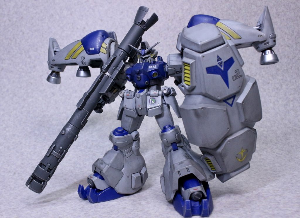 仮組みしてから足伸ばしてプロポーション変更しようかなと思ったんですがこのガッチリ感が気に入ったので特に何も弄らず一部後ハメと合わせ目消し、面出しやパテでヒケを埋めたり表面処理をしました。特にヒケは結構デカいのがいくつかあったので大変でした。バインダーの合わせ目消しはどうしても後ハメのやり方が思いつかなかったのでいっそと思って段落ちモールドにしました。そして若干失敗しました。塗装に関しては(例の如く)バトオペ2で使っていた時のカラーなんですがロービジをイメージして全体的に暗いカラーに。核バズーカ仕様のクリーム色に近い2号機とは違うMLRS仕様のグレーのカラーリングが好きなのでちょっとブルー寄りのグレーを調色しメインカラーにしました。ブルーも彩度を落とした暗め、レッドは今回抜きにして差し色的にイエローが目立つような組み合わせにしてます。関節系はガンメタ、バックパックや手の甲、腹部等はグレー。バーニアはガンメタとメタルシルバー、あとは全体塗装後にシリンダー類を中心にエナメルでシルバーとゴールドを入れています。ABS素材の部分は最初にメタルプライマーを吹いてからサフ、塗装といった感じです。割れるの怖い。(っていうか実際ちょこっと割れてます。)塗装には気を使いましたが関節はクリック機構のあるABSな上全体的にキツめなので重いシールドを構える時の保持力はなかなかですね。長時間では分かりませんが写真撮る時のポージングの保持にストレスは感じませんでした。 塗装後はウォッシングとウェザリングマスターで汚し塗装、デカールを貼って艶消しを吹いた後にドライブラシで剥げ塗装をしました。ウェザリングとドライブラシは楽しくてついついやりすぎちゃいますね。軽く汚す程度のつもりだったんですが…デカールはガンダムデカールの連邦用やアナハイム系MS用、あと昔使わなかったMG SEED系のコーションマーク等を入れました。腰フロントアーマーのマーキングは第四小隊の物です。それと塗装で赤を使わなかったので代わりにデカールで細かく赤を所々に入れました。