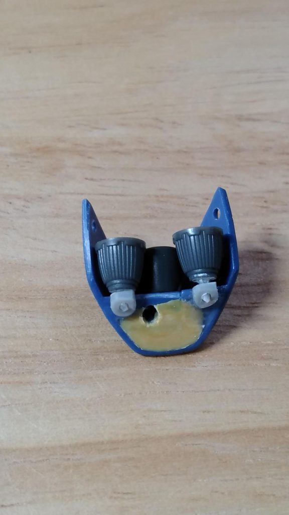 市販のバーニアに穴明けて、1mmプラ棒をつけたものを準備します。3mmのプラパイプを適当な位置に接着させ、取り付け基部にします。パテで埋めたところに穴をあけ、先程のふくらはぎダボにつけた間接パーツを入れる穴です。