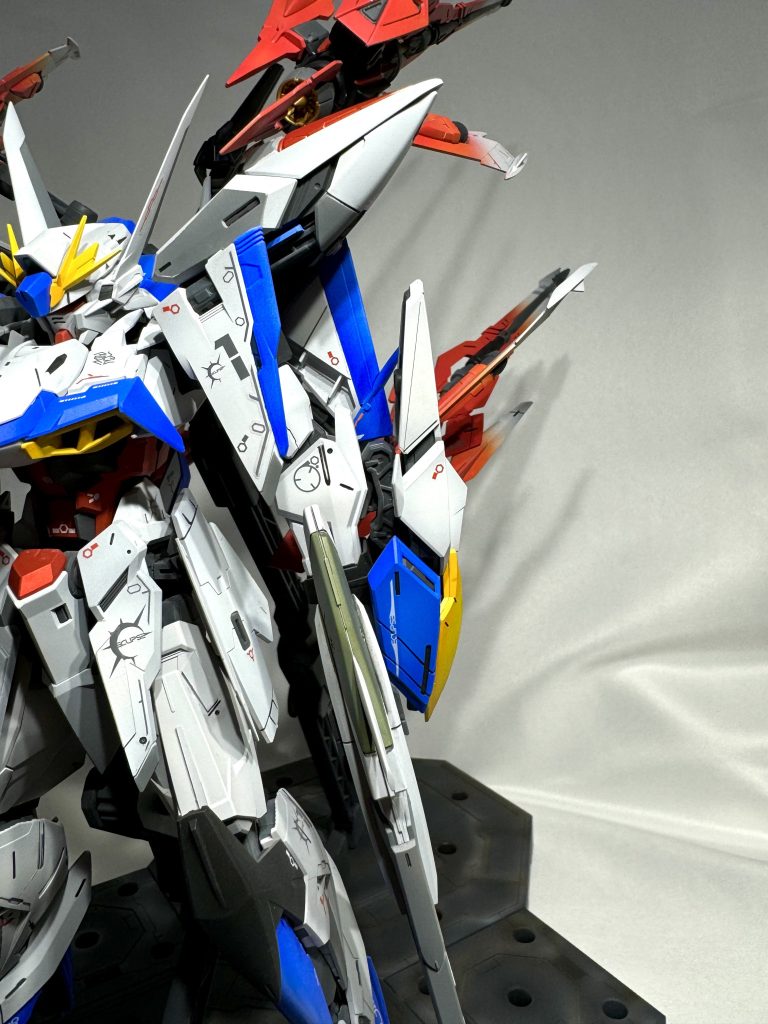 肩アーマーの後ろのウイングは肉抜きされていて薄っぺらい印象だったので、プラ板で塞いで、デカールとラインマスキングで印象を変えました。写真ですど、画像真ん中あたりの肩の後ろについているウイング(青と白)です。