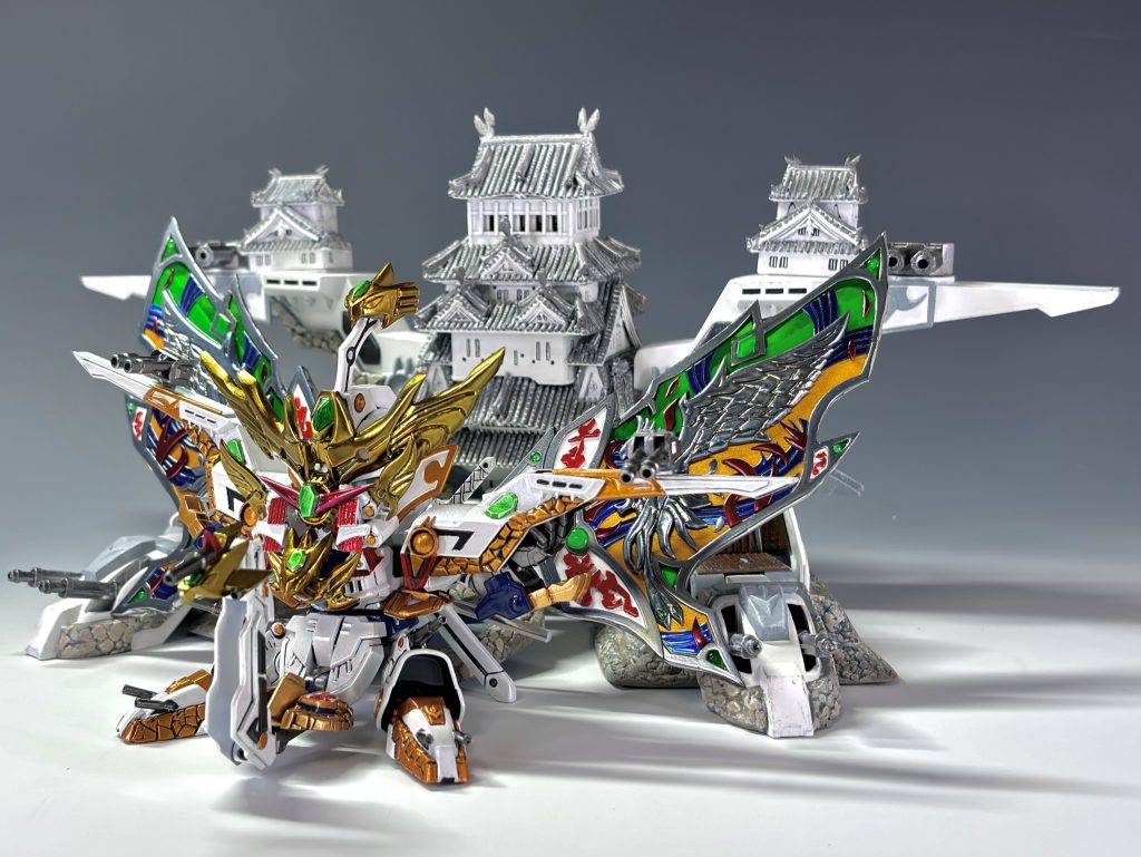 覇道大将軍との決戦時、天守が吹き飛ぶ描写(コミックW版)から號斗丸への結晶鳳凰の譲渡&50代目武者頑駄無襲名→後の世で地の民が城を改修する流れを想像しました😌※お城形態で過去作の50代目武者頑駄無との2ショットです🏯🏯従来の黄金の鳳凰部分は全て失われ、伝承を元に民が築いた屋根瓦にその名残りが見られます。