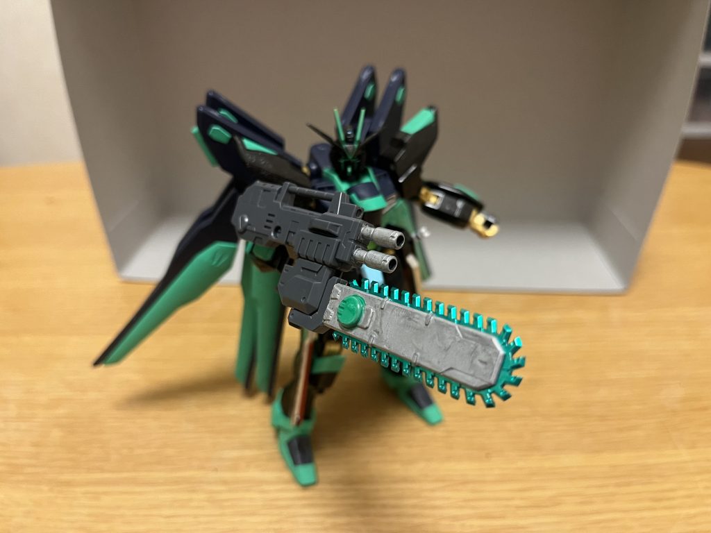 クロノスチェーンソーガン本機の専用武装であり、先端にはビーム砲2門を装備され、銃の先端部には緑色の実体刃チェーンソーが組み込まれており、銃剣のように扱う事で接近戦にも対応できる。クロノスチェーンソーガンのグリップは、銃身の左右側面に取り付ける仕組みになっている為、右手持ちだけでなく、グリップを左手持ちに付け替える事が可能。ビーム砲は、1門だけでもラミネート装甲にもダメージを与えるほどの高い威力を誇る。実体刃チェーンソーは、実体兵器ではあるが、DG細胞から得られる力によって、表面は見えないビームサーベルを纏った状態になっており、高い破壊力を発揮し、ビームサーベルと「斬り結ぶ」こともできる。チェーンソーの特性上、極端に高い攻撃力と耐久性を持つ物でなければ、剣といった相手の武装を鍔迫り合いにならずに一方的に切断してしまう事も可能。※こちらは、コトブキヤのチェーンソーを塗装して使用しました。