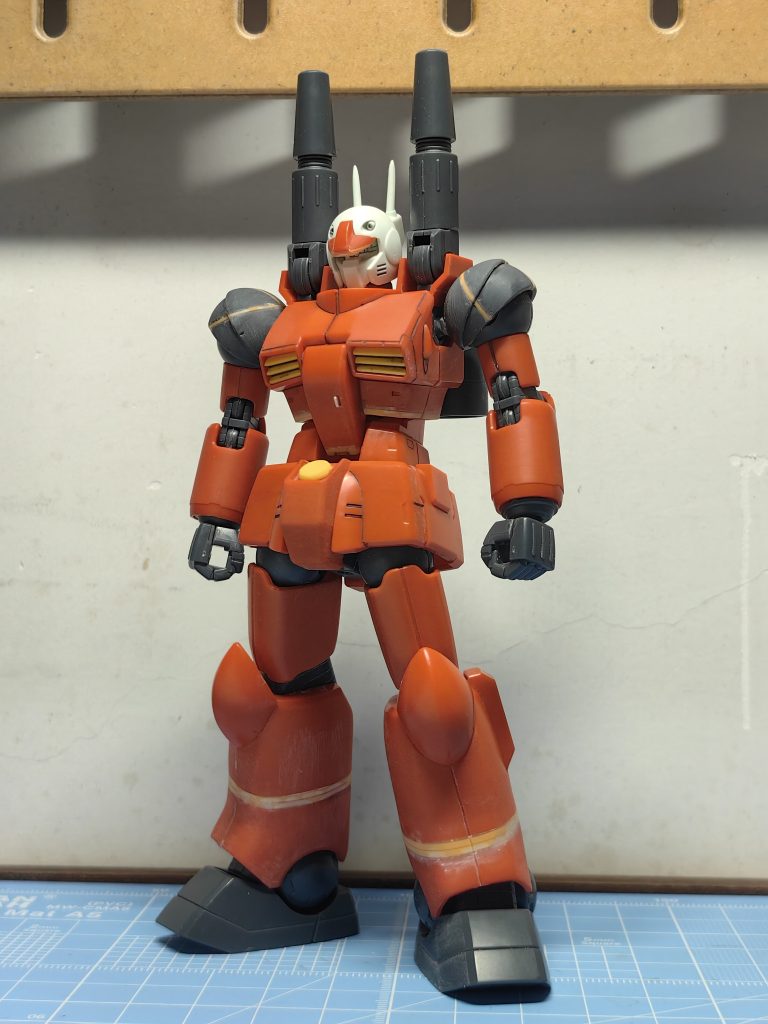 そこで、肩当ての部分に0.5ミリのプラ板を使って十字に幅を広げ、下側を厚くします。上胸の位置に1.0ミリのプラ板を使って延長します。ふくらはぎに2.0ミリのプラ板を使って高くします。もともと太ももを0.5ミリ短くしようと思っていましたが、比率を観察したらまだ大丈夫なのでその考えをやめました。また、頭部のヘルメットとモニターの距離が広すぎて、ぎこちなく見えます。ヘルメットの底に1.0ミリのプラ板を敷いて厚くし、斜面を磨いて鋭い目つきを作り出します。