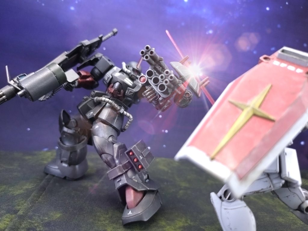 ガキィィィィィン!グフが左腕の分厚いシールドで受け止める。4本の突起が十手のように機能する。「蒼いジムはどこだ…」接触回線でジムのコクピットに声が響く。「へ…? し、知らない…」