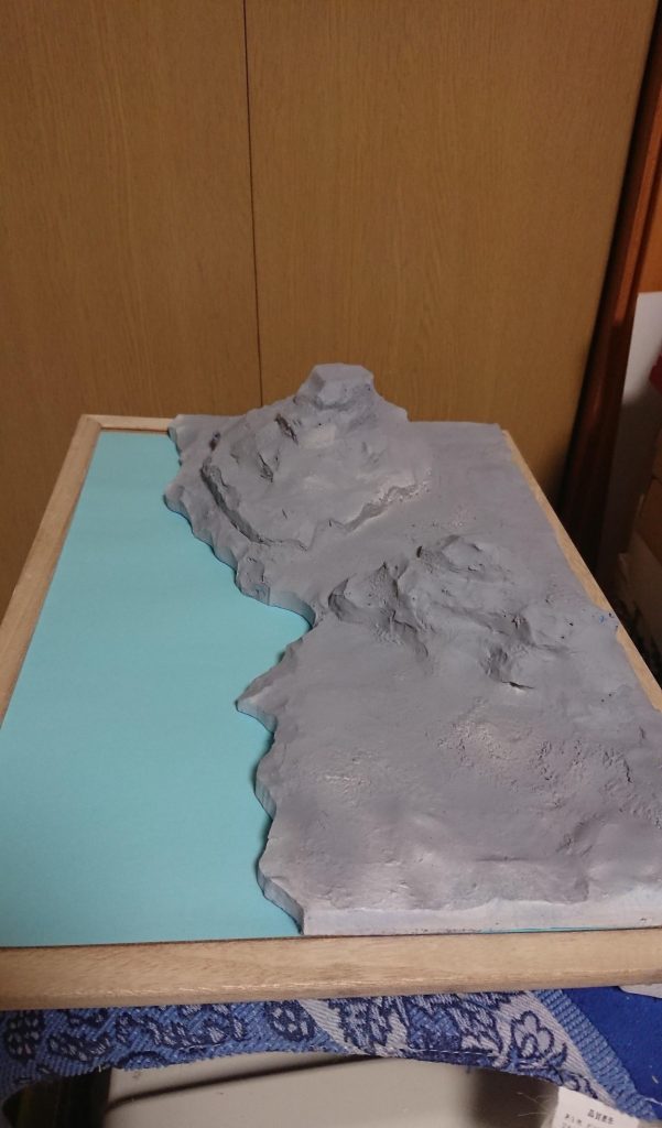 土台、制作途中。百均で買ってきた、コルクボードの額に、発泡スチロールで大まかな形を作って。表面に、水で緩くした軽い紙粘土をペタペタして。表面を歯ブラシで軽く毛羽立たせて、岩の質感を出してみました。