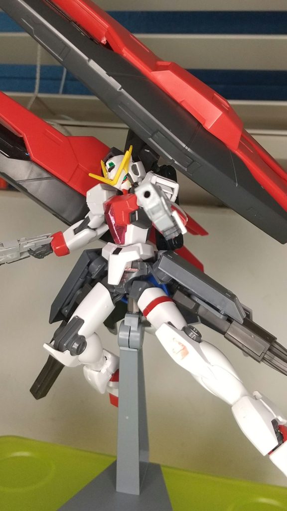 設定対ELS戦終了後、ソレスタルビーイングはダブルオークアンタの製造に多額の資金を使ったため、資金難になった。その中でELS排斥運動や、人類至上主義の人々による紛争が各地で勃発。しかし、ソレスタルビーイング地上戦力はエクシアリペアⅳ、デュナメスリペア、その他フェレシュテの機体のみで、各地の紛争を根絶するには機体が足らなかった。そこで、レティシア・アーデの提案でラファエルガンダムのプロトタイプに当たるこの機体をヴェーダから引き出し、運用することになった。元々、この機体はGNアーチャーとOガンダム、その他対イノベイド最終決戦時のMSの残骸をかき集めてつくられた武力介入用の機体で、どのマイスターの適正にも合わせて装備を変える拡張性と、全地形対応型の万能型としてのポテンシャルを有していた。しかし、搭載武装が多いことからコストが高く、ソレスタルビーイングはユニオンフラッグを改修し運用していた。当然支援は打ち切られており、その後ティエリアが自身の機体という名目で試験、完成させた。