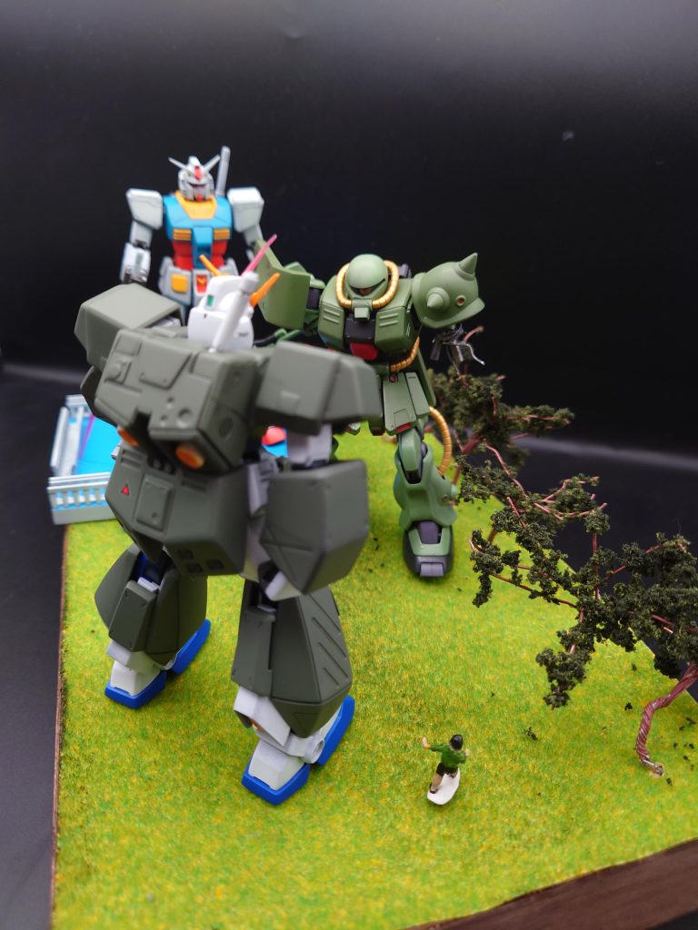 チョバムアーマーのアレックスとザクの対決シーンを遠くから見守る、RX-78-2ガンダムの図です