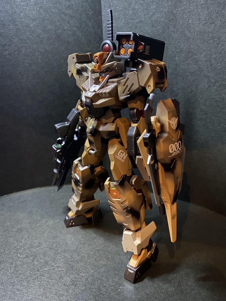 元のカーキ主体のカラーもカッコいいですが、カラバリとして発売されたこのタンカラーはさらにカラーリングの調和がとれていてカッコ良かったので、コマンドのほうは特にカラー変更や大きな改造は加えず仕上げました。と言ってもやはり目を惹くのは部分的に施したサンド迷彩でしょう。00三部作にはそれぞれ異なる迷彩を違った手法で施してきましたが、今回は砂漠迷彩をエアブラシの細吹きにて描いてみました。1/144スケールでは若干線が太いかなとも思いましたが、初めてだったのでいつも使っている0.5口径のノズルで挑戦してみました!