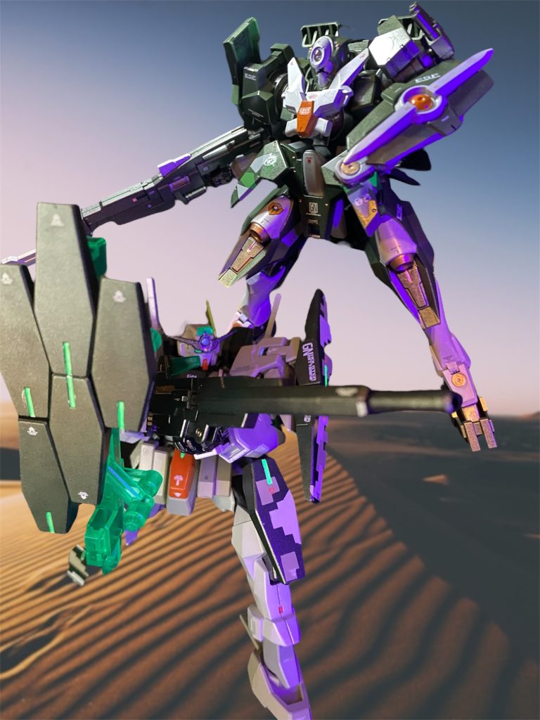 出撃したフィールドは砂漠地帯の中の秘密基地という設定がなされていた。クリア条件は目標となる試作型MSの防衛だが、このミッションに制限時間が設けられていない。となると敵部隊の殲滅がクリア条件か?と訝しげにマリオは推察した。明示されていない達成条件を推理しながら戦うことも、このミッションの一環だろう。 早速、稜線の向こうから早くも敵先鋒が姿を現したが、超高高度射撃銃type Kの餌食となった。三男セリオ・レナートはケルディムガンダムtype BGFを操り小隊の後衛狙撃手を務める。かつてテストミッションで相対した憧れの3代目メイジン・カワグチから贈られたケルディムサーガを、メイジンへのリスペクトを込めつつリカスタマイズしたガンプラだ。サーガ譲りのピクセル迷彩が施された機体は精密射撃戦に特化しており、オプション装備として用意した大型スナイパーライフルとの組み合わせにより、超遠距離精密狙撃を得意としている。その狙撃手を背後から潰そうと上空から降下してくる機体があれば、瞬く間にそれは潰されてしまった。次男フリオ・レナートが駆る機体はかつて兄が使ったストライカー・ジンクスを遊撃手仕様にカスタマイズしたACTVジンクス。原型機からは機動性に重点が置かれており、より取り回しの良い武装で、どんな敵にも素早く対応する。