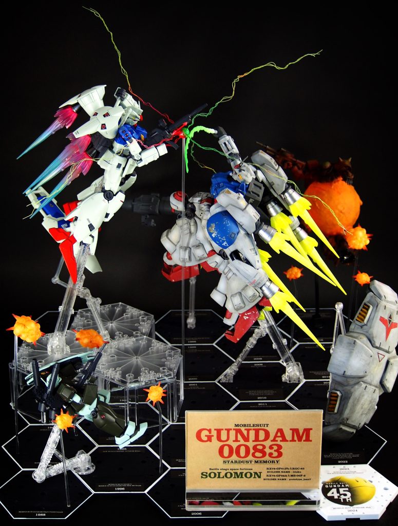 完成図です。襲いかかるGP02に迎え撃つGP01。私が作成したのはサイサリスと奥のザクだけで、あとは全て友人が作成。土台には、ガンダム45年の歴史が並べられています。