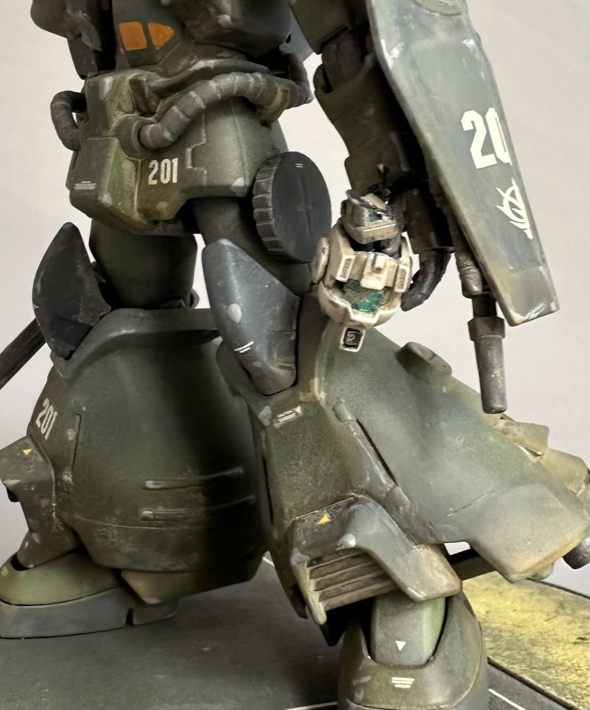 左手に鷲掴みされたジム頭は、どちらのご家庭でも1個は余っていると言われるるHGUC陸ジムのものです。地味にトサカカメラをくり抜きメカを突っ込んだり、ゴーグルを割ったりと手を入れています。切り取られたばかりの首関節の切断面はぬらぬらと光沢を持っています。どちらかというと理知的なヤーコブ隊長は敵MSの首を狩る様な蛮行はあまりしなさそう…。多分、こんな感じなのかと妄想↓ヤーコブ隊メカニック「隊長!連邦のMSを倒したら頭部ヘッドだけは切り取って持ち帰ってきて下さいね!あれ、光学センサーとか演算チップとか宝の山なんですよ!精密機器は残念ながらジオン製より連邦製の方が高性能なんですよ〜!!でもね結構ポン付けでうちらのMSやらAFVに流用できるんですよ!!ね!だから、必ず首だけでもぶんどって来てくださいね!!ホントは本体ごと持ち帰って来てもらえればジェネレーターも…」