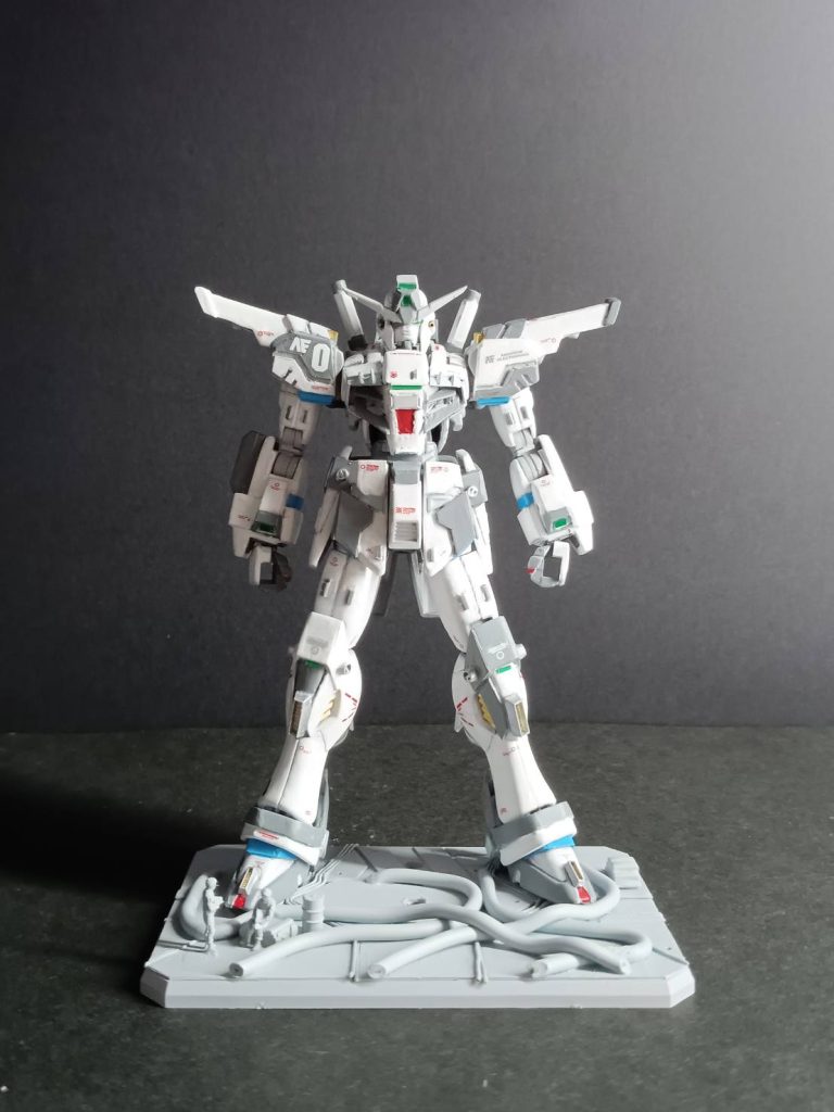 試験場 - 初動テスト開始AE社の秘密試験場にて、レイ・ホークウッドがガンダムドライグの初動テストを開始する。レイは同僚であるハンス・ネオ・ハルトマンのハーディガンと模擬戦を行い、ドライグの性能を引き出そうとするが、最新システムの不安定さに苦戦していた。レイ：「なんて扱いづらいんだ！こんな機体で戦えっての！？」ハンス：「ハハッ！レイ！新型の調子が悪いじゃないか。それともビビっちゃってる？」クラリッサ：「冷静に！レイ、落ち着いて。まだ初動テストよ。システムが安定すればもっと扱いやすくなるはずよ。データを集めながら操作して。足りない部分はネオサイコミュが反応するわ」レイ：「クラリー、これじゃまともに動けないよ！」その時、突如としてレーダーに反応があり警報が鳴り響く。敵だ。試験場にクロスボーン・バンガードの部隊が襲撃を仕掛けてきた。部隊を指揮するのはガンマッド少佐。彼はベルガ・バルスに搭乗し、デナン・ゾンとデナン・ゲーの部隊を率いていた。レイ：「ハンス、敵襲だ！こんなに近くまで？ステルス機なのか！？」ハンス：「！敵だって？！やるしかないのかよ！応戦する！」