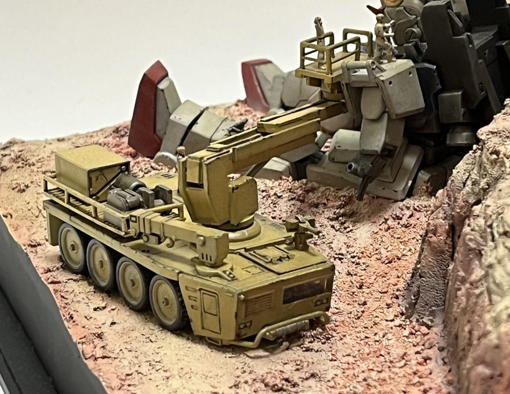 高所作業車。タカラトミー1/144マイクロスケールボトムズ/AT&ビークルのAT輸送トレーラーを改造。高所作業用アーム、カーゴデッキ、自動発射式チェーンガン、上部ハッチを追加。手前の元々のクレーンアームはカーゴデッキへの荷物の上げ下ろし用という事に。MS用に作られた現地修理回収対応車両という設定です。