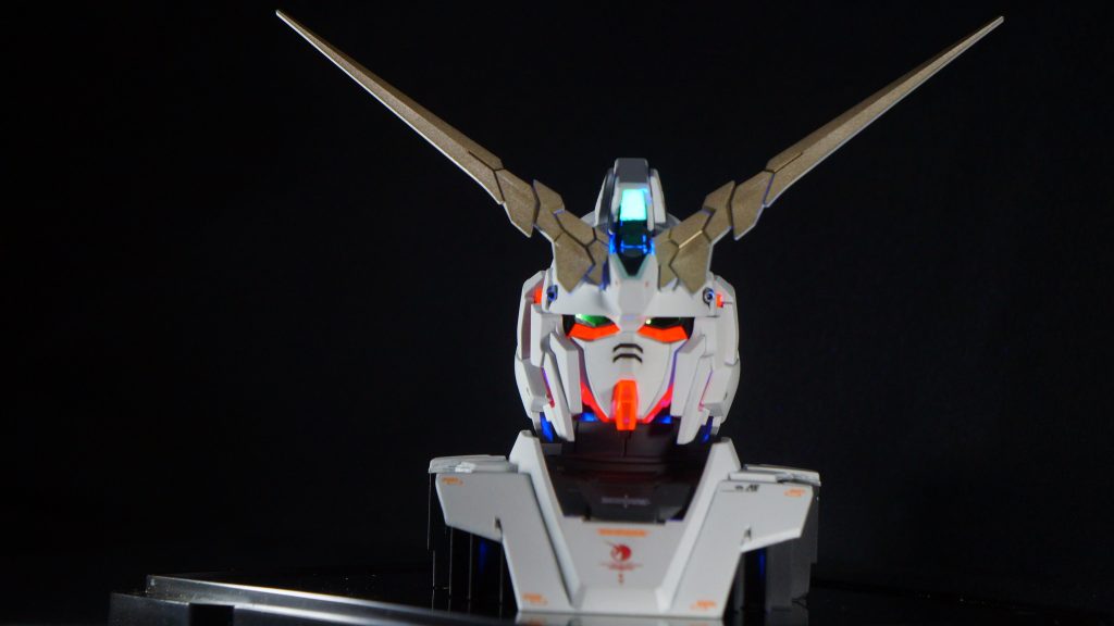 サイコフレームはUVライトで発光します。とさかのグリーンのカメラ部は元は外装と同じ整形色のパーツでしたので、たまたま手元にあったお菓子の箱（がいこつの棺桶みたいなケース）がクリアグリーンのプラだったので、切り取って貼り付けています。こちらもUVライトで光るというミラクル！当時はUVライト持ってませんでしたので、知らずに使用していました。ツインカメラもこれに置き換えたらよかったですね。光り方が全然違います…。ちなみにちらちらと青く光っているのは外装のプラにも蛍光成分が含まれているようで、塗装されてないところが光ってるようです。(zaku-kao10)