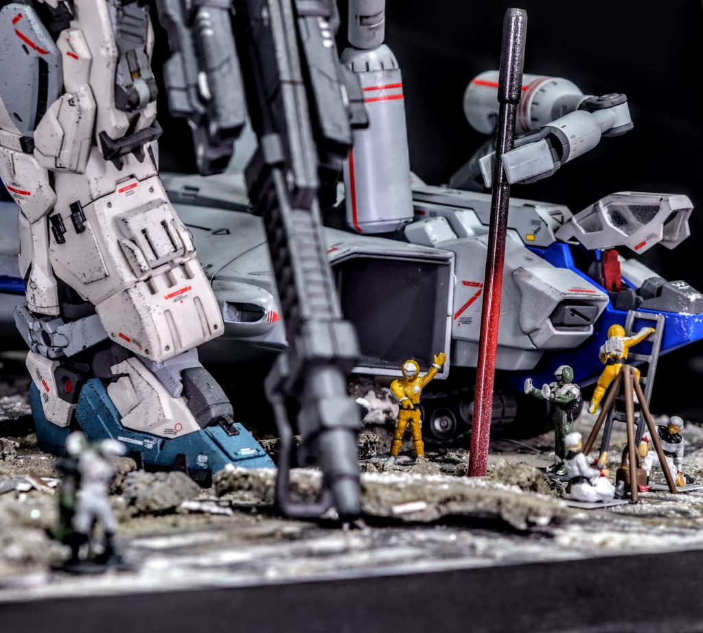 赤熱したバレルを地面に刺して冷却中ですが、それを利用して戦闘を終えたジオン兵と連邦兵が暖をとっています