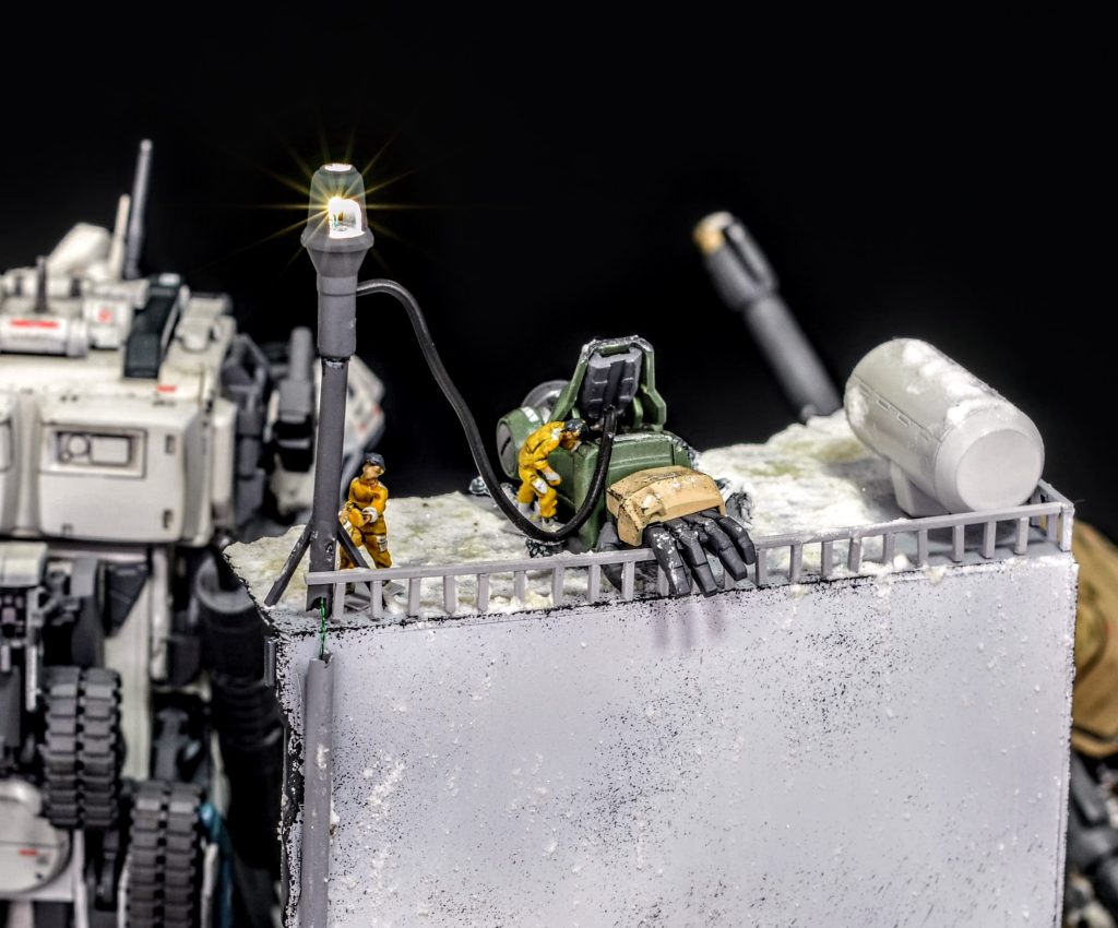 戦闘に巻き込まれ崩壊した廃ビルの屋上では、ジェットコアブースターⅢに乗り合わせた技術兵がおり、ちぎれて転がったザクの腕の残留エネルギーを利用して照明灯を設置しています