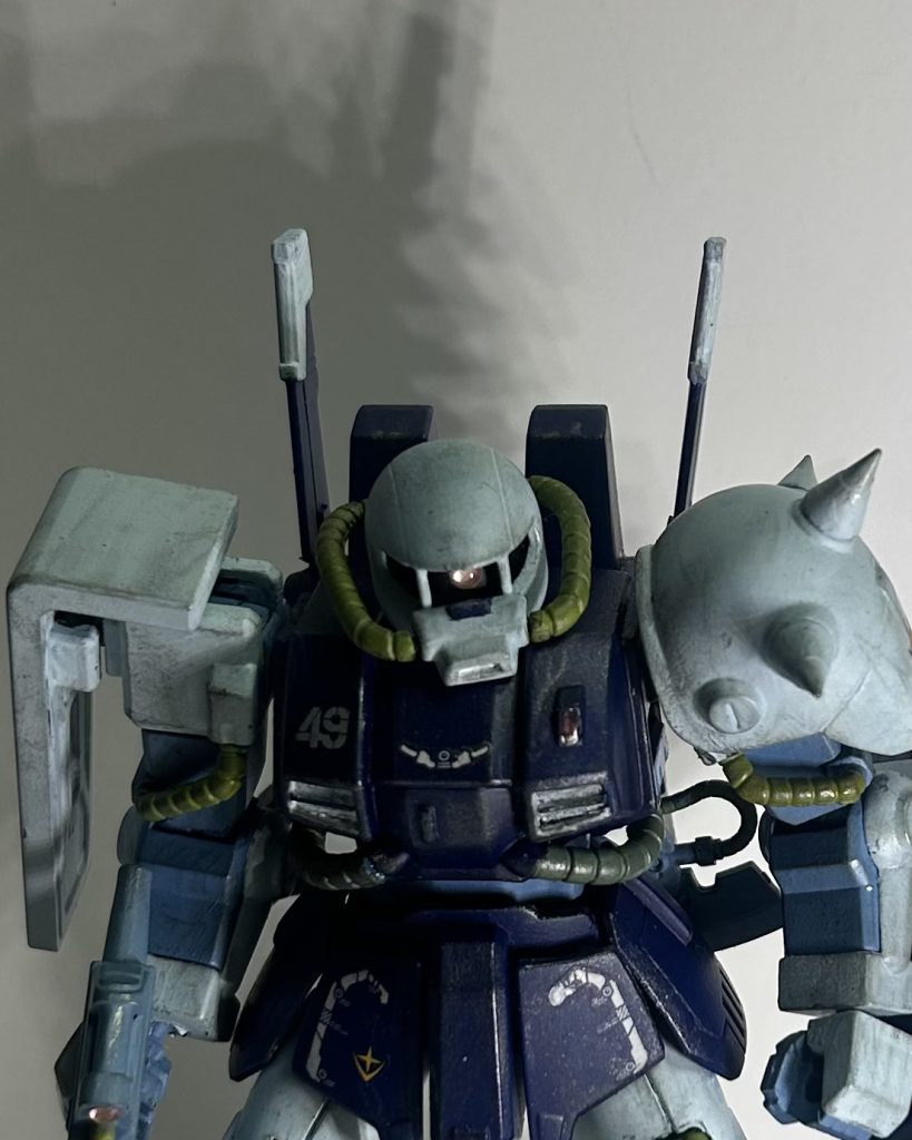 後は汚しとデカール。デカールは一年戦争の生き残りのベテランパイロットを燻し銀的にイメージして派手にならないように。そしてレンズ部分に当たりそうな場所にクリアレジン。今回それで最も成功したかなと思う点はモノアイのレンズとライフルのスコープレンズですね。作り方としては3Dメタリックシールにクリアレジンを乗せて固めただけ。それだけでも良い感じに表面張力で半球状になってくれるし、何よりめっちゃ集光してくれる……、レンズの作り方今度からこれでイイかもしれない……。パッケージのサンプルが頭でっかちに見えるのは多分シールのせいだと思うのです。