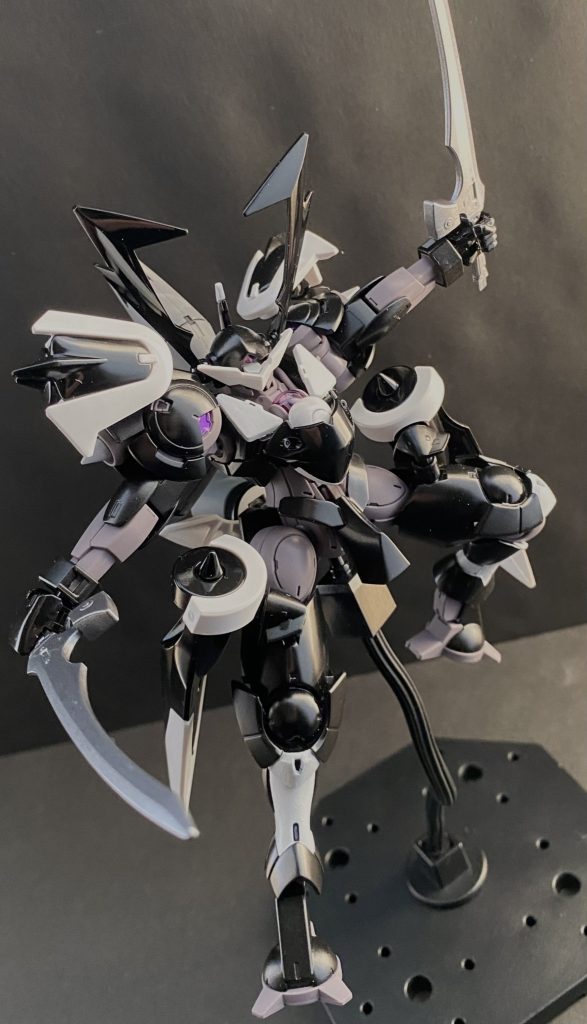 「なんとっ！此方の土俵に乗ってくれるか！…良いぞ！マリィ･クルス･ジンネマンッ！」　私、グラハム･エイカーが御相手するっ！そう言って、漆黒のハインドリー「スサノオウ」のコクピットの中で、グラハムは叫ぶ。吐血しながらなのは、加速性能に振り切ったカスタマイズが施された機体のGによるものだ。向かってくるマリィのディランザを、メインモニターいっぱいに捉えながらグラハムは叫ぶ。「エアリアル亡き今！地球寮、いや。株式会社ガンダムにおいて、私が！私こそが！…ガンダムだッ！」　ガンダムはっ、敵！…かつて強化人士被検体だったマリィの脳裏に忌まわしい記憶が甦る。「…お前も、ガンダムかッ！」　忌まわしい過去の記憶を振り払うように、彼女の左手は目にも止まらぬ速さでパネルを操作すると、次々にAIシステムをオンラインにしていく。　彼女の操るMS。ディランザ･カッティーヤは四枚の羽、バインダーを広げると、複数の小型ガンビット「コラキ」を展開する。ペイル社のMS、ファラクトに搭載されていたものと同等のものだ。その「コラキ」をジェタークのAIが操り、目前のハインドリー、スサノオウを絡め取るように広がっていく。スサノオウのコクピットの中で男は目を剥く、しかし、次の瞬間、スサノオウの動きにコクピットのマリィは驚く。　漆黒のハインドリーは、その機体の周りにまとわり付くよう展開されたコラキを次々と切り払っていくのだ。通常、MSが何かをする場合、一度モニター内に捉え、ロックオンするのが一般的だ。それを行うにはカメラなり機体なりをその方向に向けなければならない。だが、目の前の機体は、周りのコラキが全て見えているかのように、黒い竜巻のように、MSから見れば小さいコラキを、両の手のブレードで両断していく。その視界に捉えることもなく。「…ガンビットか、…だが、私は常にッ、心眼を鍛えているッ！」　漆黒のハインドリー、スサノオウのコクピットの中でグラハム･エイカーは吠える。