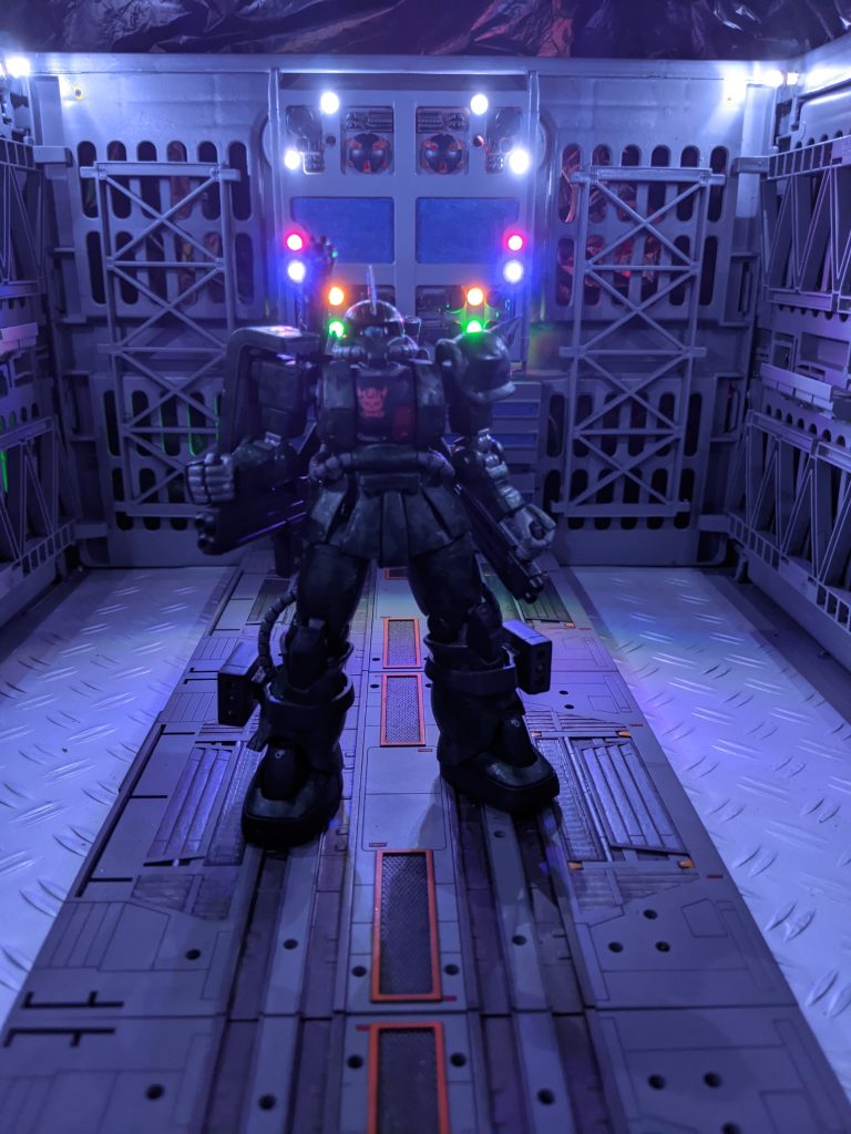 今まさに飛立とうとしているHLSのブースターにビーム砲を打ち込もうとしているジムの姿を…彼の不幸は彼の性根が善性だったことだろう。数十人の人間が殺されようとしているのを見捨てることができない人間だった。だから気が付けばスロットルを踏み込んでいた。残り少ない推進剤でザクが飛ぶ。背後から不意打ちを受けたジムはそのままザクに羽交い絞めにされたまま諸共に地面を転がった。問題は位置関係だ。ジムは射程距離の短いビーム砲でブースターに真正面から打ち込もうとしていた。そこに背後から組み付いて前に転がれば…次の瞬間ブースターの炎に二機は包まれた。