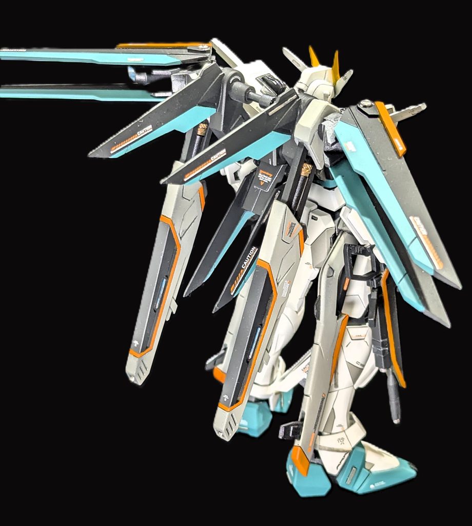 スタイル改修のポイントは、ヘルメット前後1mmプラ板による延長。肩アーマーは軸に通す構造にし、前腕とは独立しています。胴体部分は5mmほど延長。脇腹部分はMGEXストフリを参考にほぼ作り変えました（後述の製作写真で確認できます）脚部は大腿部を3mm延長。ふくらはぎ部分のスラスターはプラ材でスクラッチし、ディテール増量しています。この他全身に小さいプラ材を貼り付けてディテールアップしています。脚部のスジボリは塗り分け目的も兼ねて施しました。また、バックパックは再構築した形状にしています。バラエーナ砲は15mm程度プラ角材で延長し、金属製のネジパーツもいれてみました。