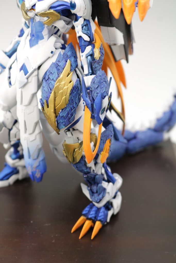 脚部をアシンメトリーのデザインにしたのは、ダイの大冒険のマームの魔甲拳のアムドをイメージしています。太ももの装甲などの鱗模様は、2mmのプラバンを鱗の形にカットして、流し込みの接着で1枚1枚貼り付けました。厚みと立体感を出すために無駄に2層構造になっているので脚部、背面ユニット、尻尾、腕部で、計1000枚以上は張り付けてると思います。左手の武器は、ドラゴンクエストの手甲タイプのドラゴンキラーをイメージししたというより、ドラゴンキラーを作りました。やっぱりドラゴンキラーはこのタイプが好きです