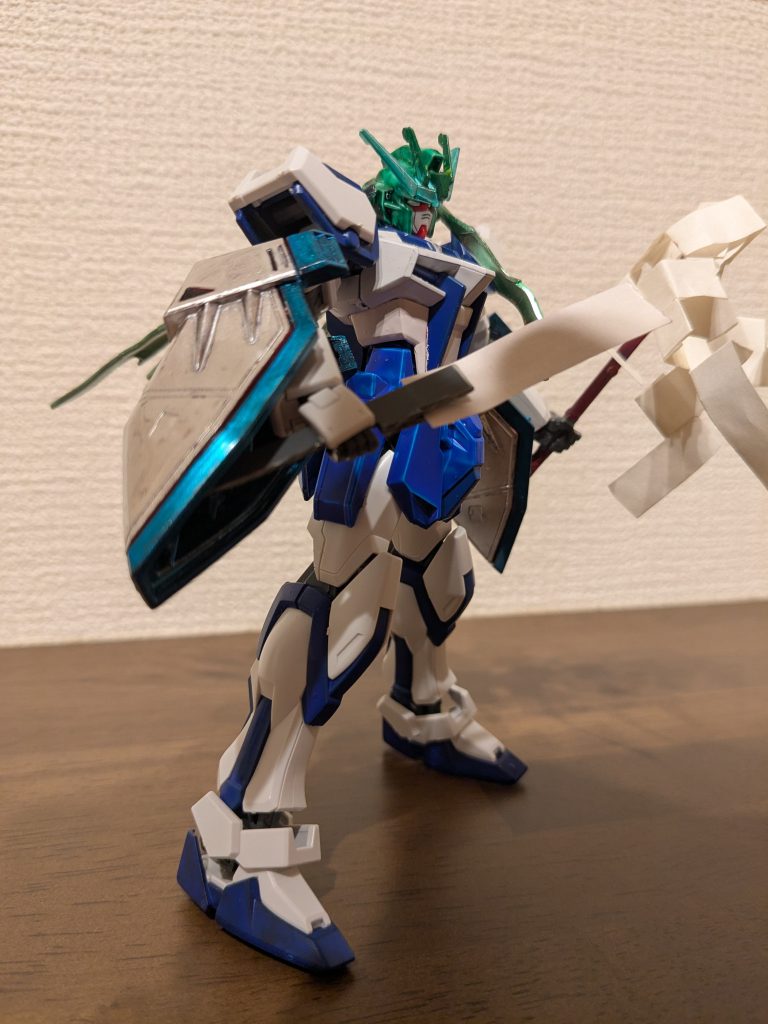 サイドショットその1本体ガンダムホワイト、ガンダムブルーでほぼ完了です。頭はクリアグリーンベースにメインアンテナとカメラアイはメタルグリーン、サブアンテナはグリーンと、頭だけで緑３色！早苗が頭に付けてる飾りの色をここに出したいという娘の要望です。御祓い棒はランナータグを使用した持ち手に、紙部分を100均木目テープの裏紙をちょうど良い大きさに切って挟み、右手に持たせてあります。エピオンの肩はコスモメタブルーとシャインシルバーに塗って腕を挟み込み、巫女装束の袖に見立ててみました。無加工でピッタリ装着できているので、色々動きもつけられます。