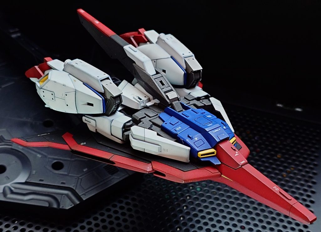 スジボリ、塗り分けしてゴチャゴチャ感を出してみました。羽根部分は3段重ねで組み立てていく構造。このキットはココが最も大変な箇所だと思います。合わせ目が消しづらい構造なので、後ハメ加工で塗り分けしました。この羽の後ハメ加工は中間パーツの一部を切り取って先端パーツを挟む構造、そして根元の尾翼のパーツに引っ掛けるようにします。詳しい解説はブログにまとめてみましたので、ご興味があればこちらからどうぞ。https://ajimaru.org/plasticmodel/hguc_zgundam_atohame/ 