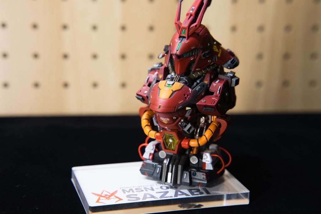 土台は100均のアクリル板と、Canvaでつくった画像をプリントアウトして貼り付けました。サイズ感がちょうどよいので、デスクにも車のダッシュボードにも飾りやすいので、普段のガンプラと違う場所に飾れるのがいいですね